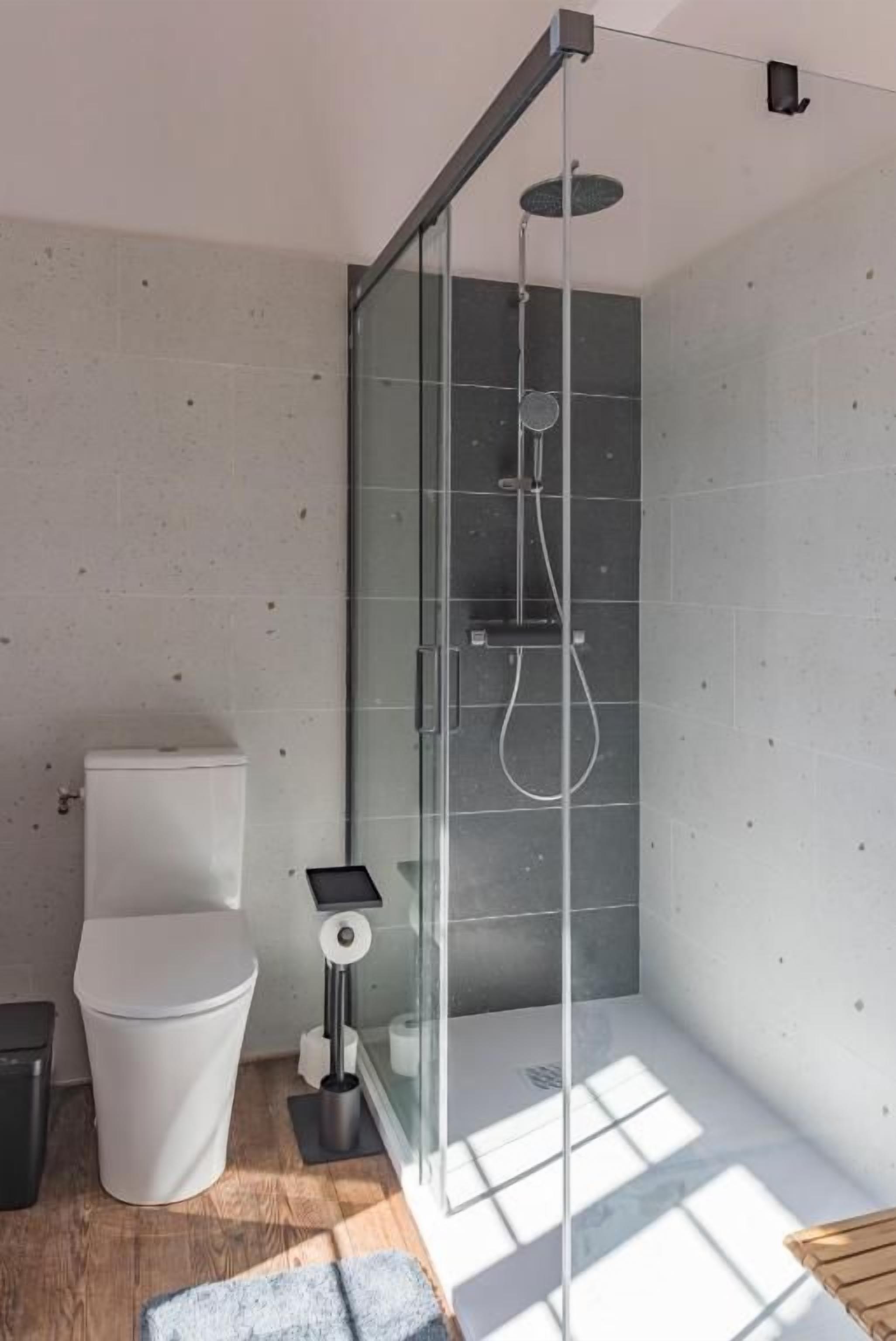 A modern bathroom with a glass shower enclosure, a toilet, and a bidet.