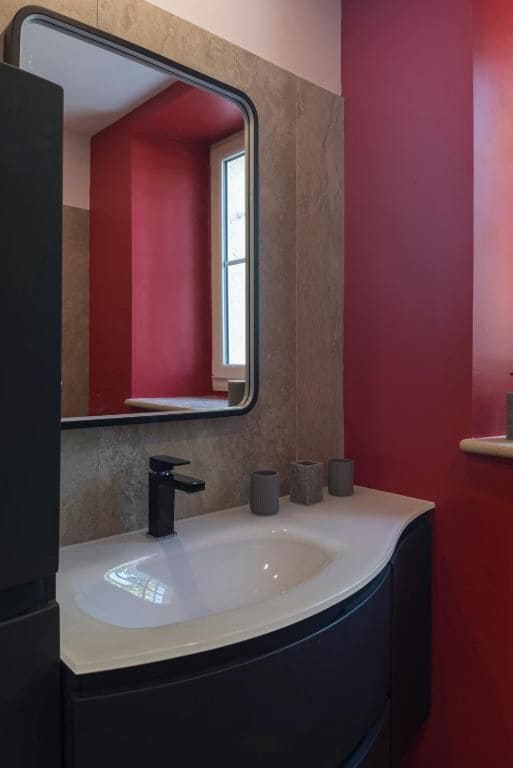 A bathroom with a white sink, a black faucet, and a mirror.