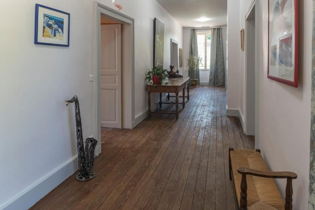 Un couloir doté d’un plancher en bois, d’un banc, d’une table avec une plante et de tableaux encadrés accrochés aux murs.