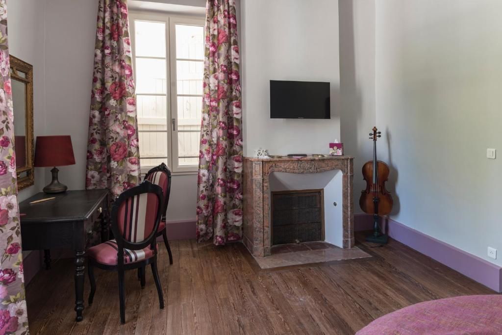 Una habitación con chimenea, televisor montado en la pared, un violín y un comedor con sillas y una mesa.