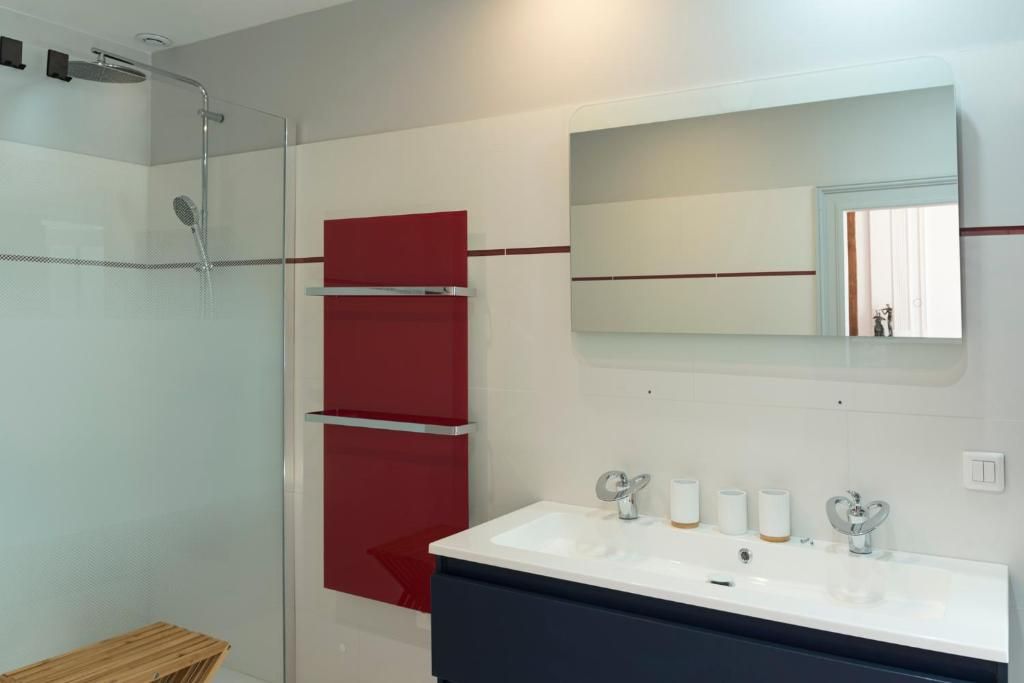 A bathroom with a glass shower enclosure, a white sink with two faucets, and a mirror above the sink.