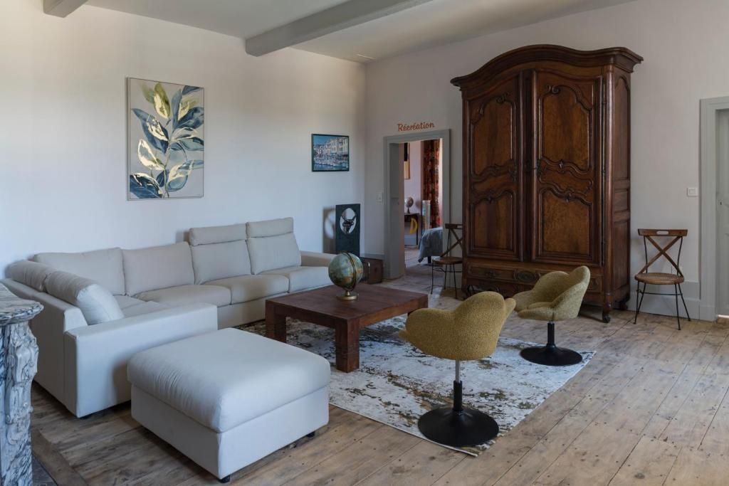 A living room with a sofa, armchair, coffee table, and a large wooden cabinet.
