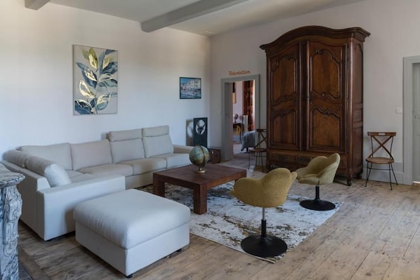 A living room with a sofa, armchair, coffee table, and a large wooden cabinet.