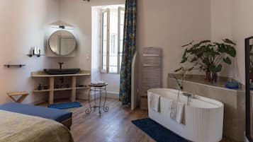 Ein modernes Badezimmer mit Badewanne, großem Spiegel, Waschbecken und einer Topfpflanze.