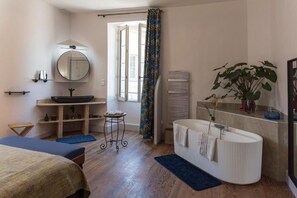 Ein modernes Badezimmer mit Badewanne, großem Spiegel, Waschbecken und einer Topfpflanze.