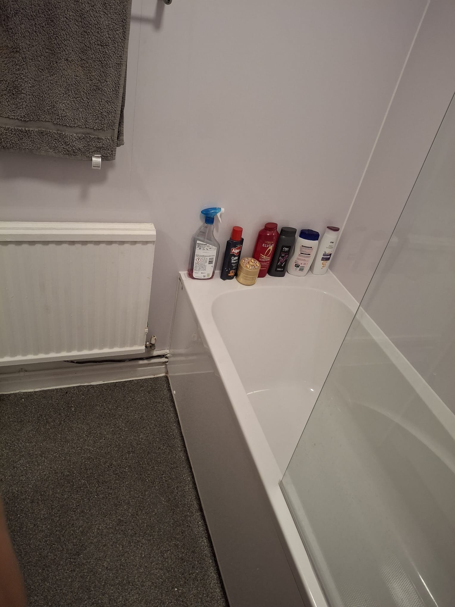 Un bagno con una vasca, un portascopevoli e uno scaffale con diversi articoli da toilette.