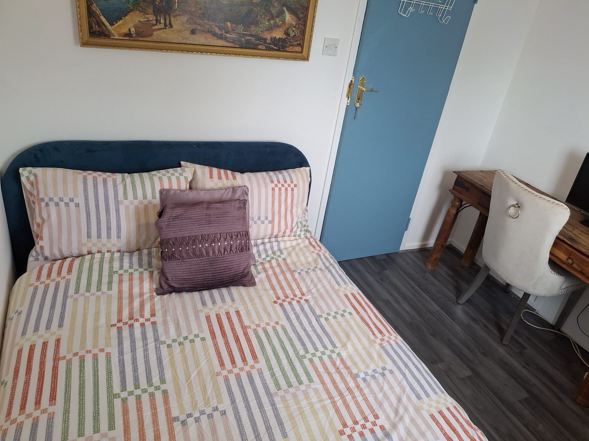 Una camera da letto con un letto, una porta blu, un tavolino e una sedia.