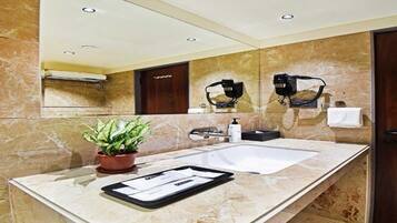 Un baño moderno con un espejo grande, un lavabo y una planta en maceta.