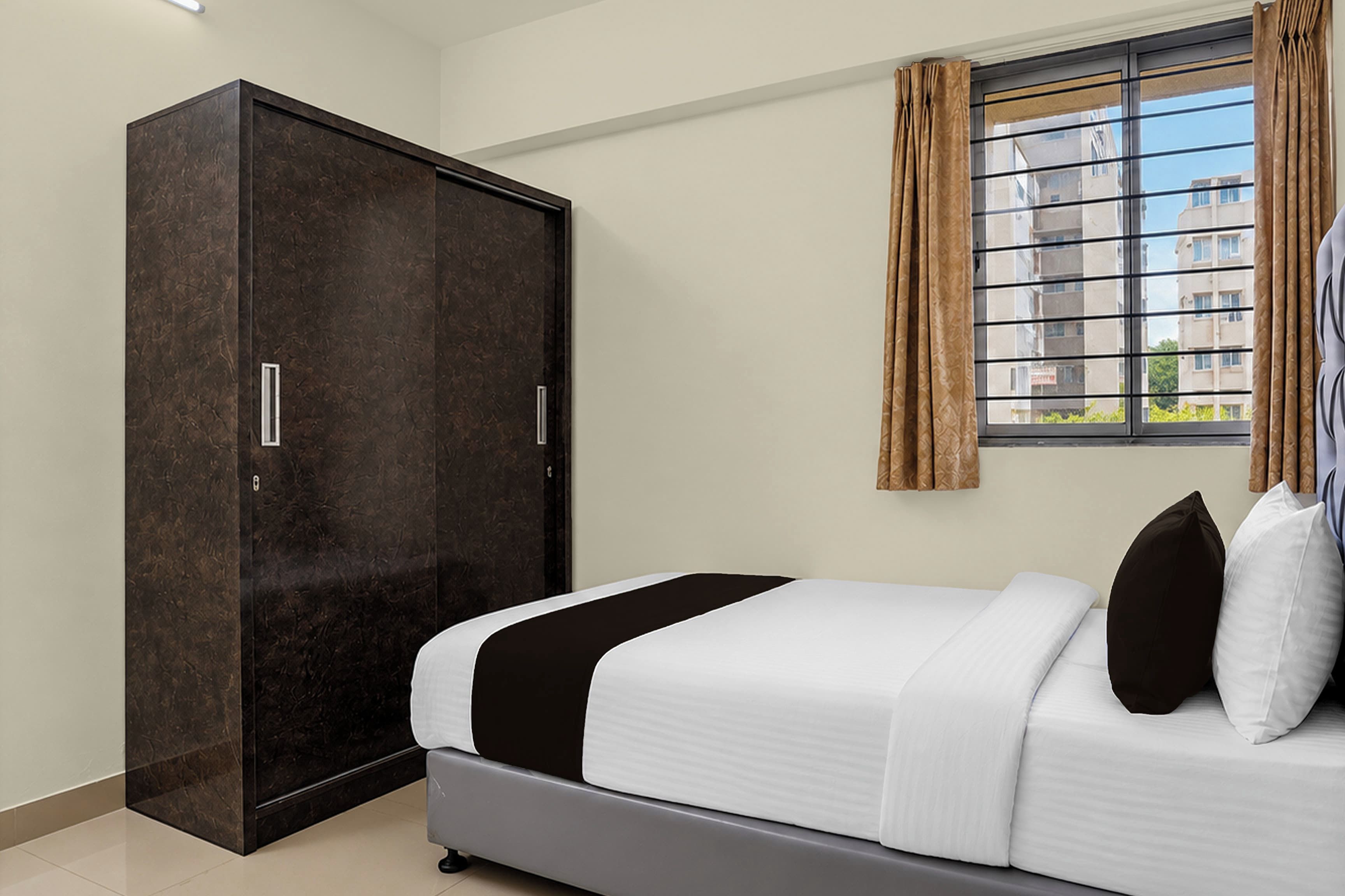 Un dormitorio con cama, armario y ventana con cortinas.