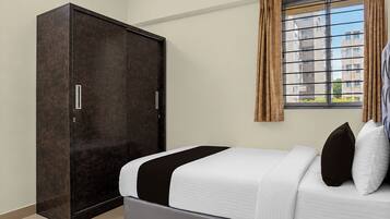 Un dormitorio con cama, armario y ventana con cortinas.