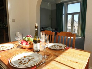 Una mesa de comedor con platos, una botella de vino y copas, en una habitación con vistas a un balcón.