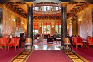 A grand hall with ornate columns, a patterned carpet, and a variety of seating arrangements. - Apartment 'Gîte La Rosa - Domaine Les Bois De' with Shared Pool, Shared Terrace and Wi-Fi (Sixt-sur-Aff)