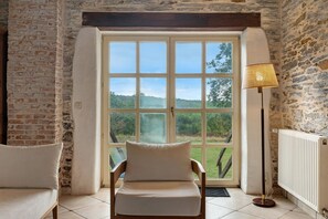 A room with a large window, a chair, a floor lamp, and a radiator. - Apartment 'Gîte La Rosa - Domaine Les Bois De' with Shared Pool, Shared Terrace and Wi-Fi (Sixt-sur-Aff)