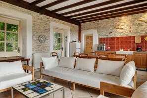 A cozy room with a sofa, a coffee table, and a kitchen area with red tiles. - Apartment 'Gîte La Rosa - Domaine Les Bois De' with Shared Pool, Shared Terrace and Wi-Fi (Sixt-sur-Aff)