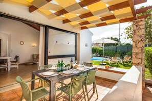 Un espace de restauration en plein air avec une table dressée pour deux personnes, des chaises et une vue sur une piscine.