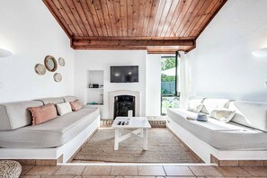 A living room with a fireplace, two sofas, a coffee table, and a TV mounted on the wall. - Villa Levante - Two Bedroom Villa, Sleeps 4 (Albufeira)