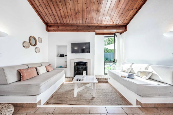 Un salon avec une cheminée, deux canapés, une table basse et un téléviseur fixé au mur.