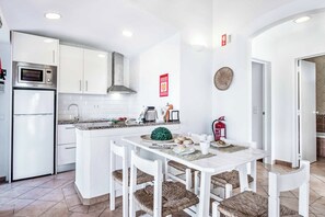 Une cuisine moderne avec des meubles blancs, un four à micro-ondes encastré et une hotte de cuisinière en acier inoxydable.