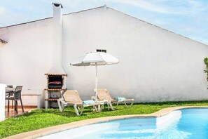 A poolside area with a barbecue grill, lounge chairs, and an umbrella. - Villa Levante - Two Bedroom Villa, Sleeps 4 (Albufeira)