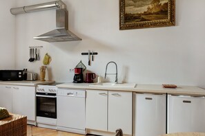 A modern kitchen with white cabinetry, a stainless steel range hood, a microwave, a toaster, and a coffee maker. - Gîte 'Du Bois' with shared pool (Sixt-sur-Aff)