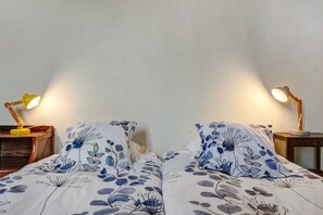 A double bed with floral bedding, two bedside tables with lamps, and a plain wall. - Gîte 'Du Bois' with shared pool (Sixt-sur-Aff)