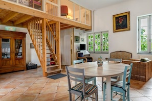 Ein Essbereich mit Holztisch und Stühlen, einer Treppe und Blick auf Grün durch große Fenster.