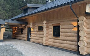 Una cabaña de madera con cimientos de piedra, revestimiento de madera y techo de metal.