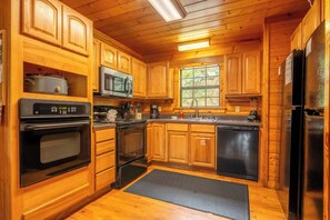 Eine Holzhütte mit einer Küche, inklusive Backofen, Mikrowelle und Kühlschrank.