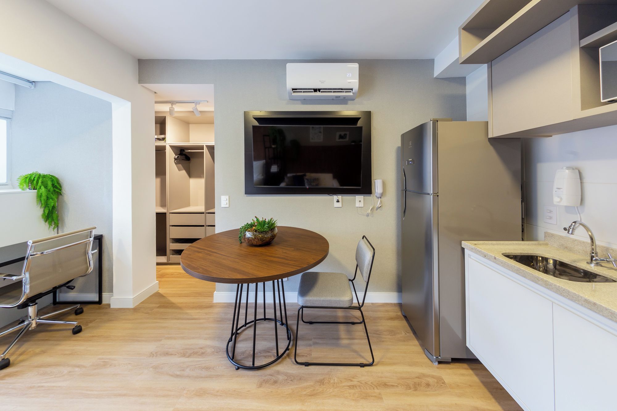 Een moderne keuken met een inbouwkoelkast, een flatscreen-tv en een eethoek met een ronde tafel en stoelen.
