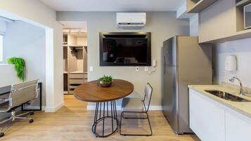 Een moderne keuken met een inbouwkoelkast, een flatscreen-tv en een eethoek met een ronde tafel en stoelen.