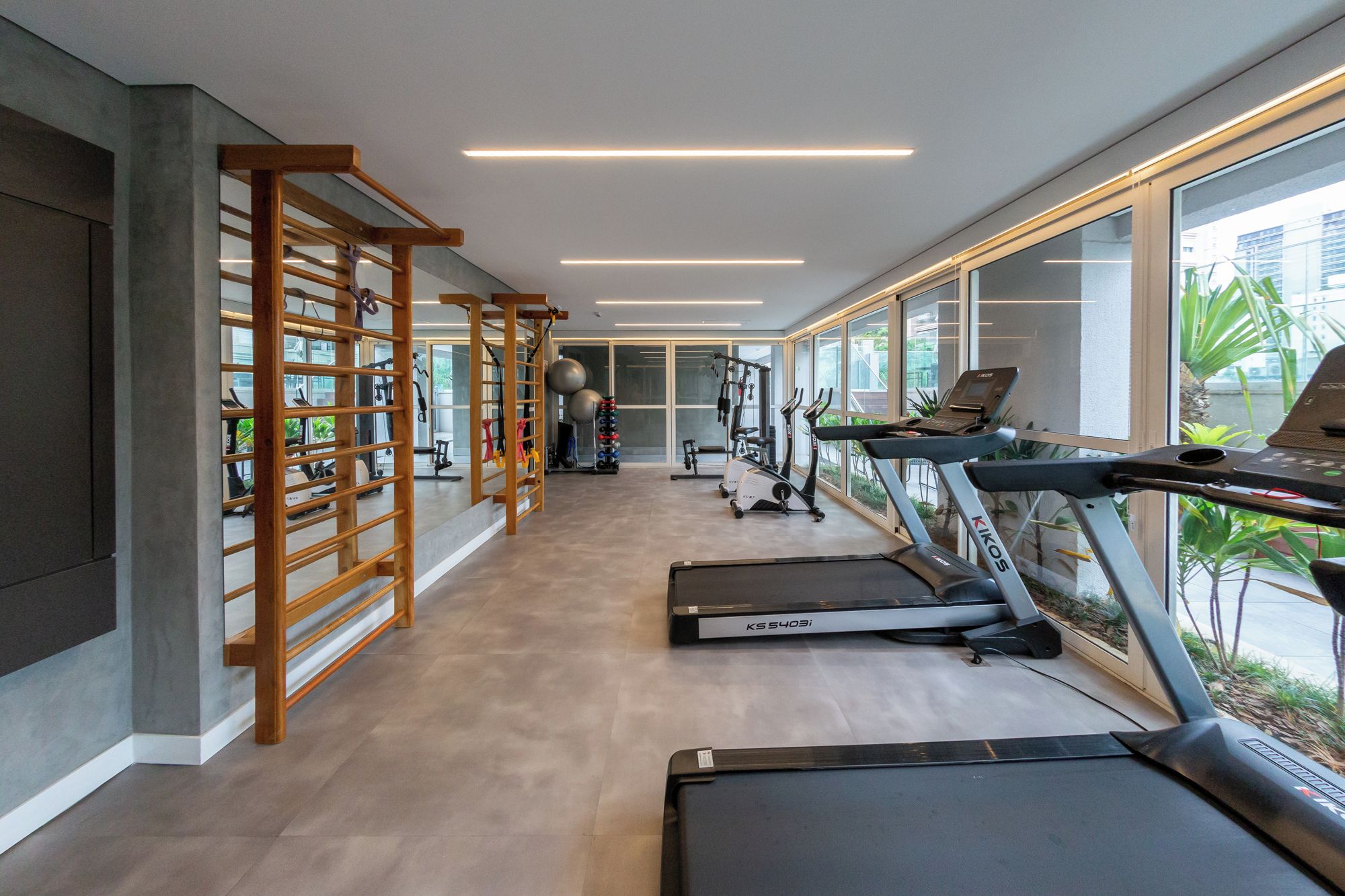 A modern gym with treadmills, exercise equipment, and large windows.