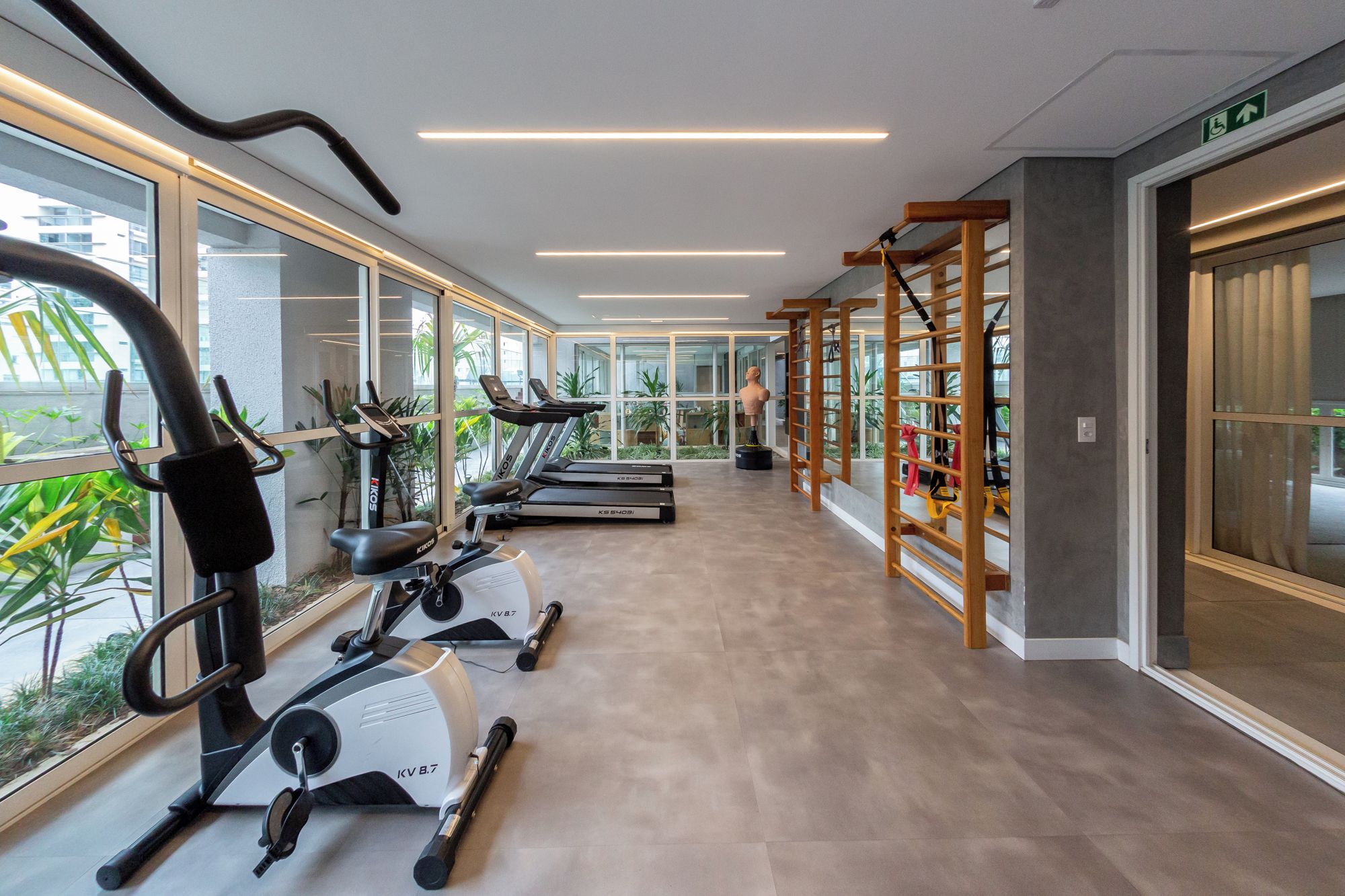 Een fitnessruimte met cardioapparaten, een loopband en een klimmuur.