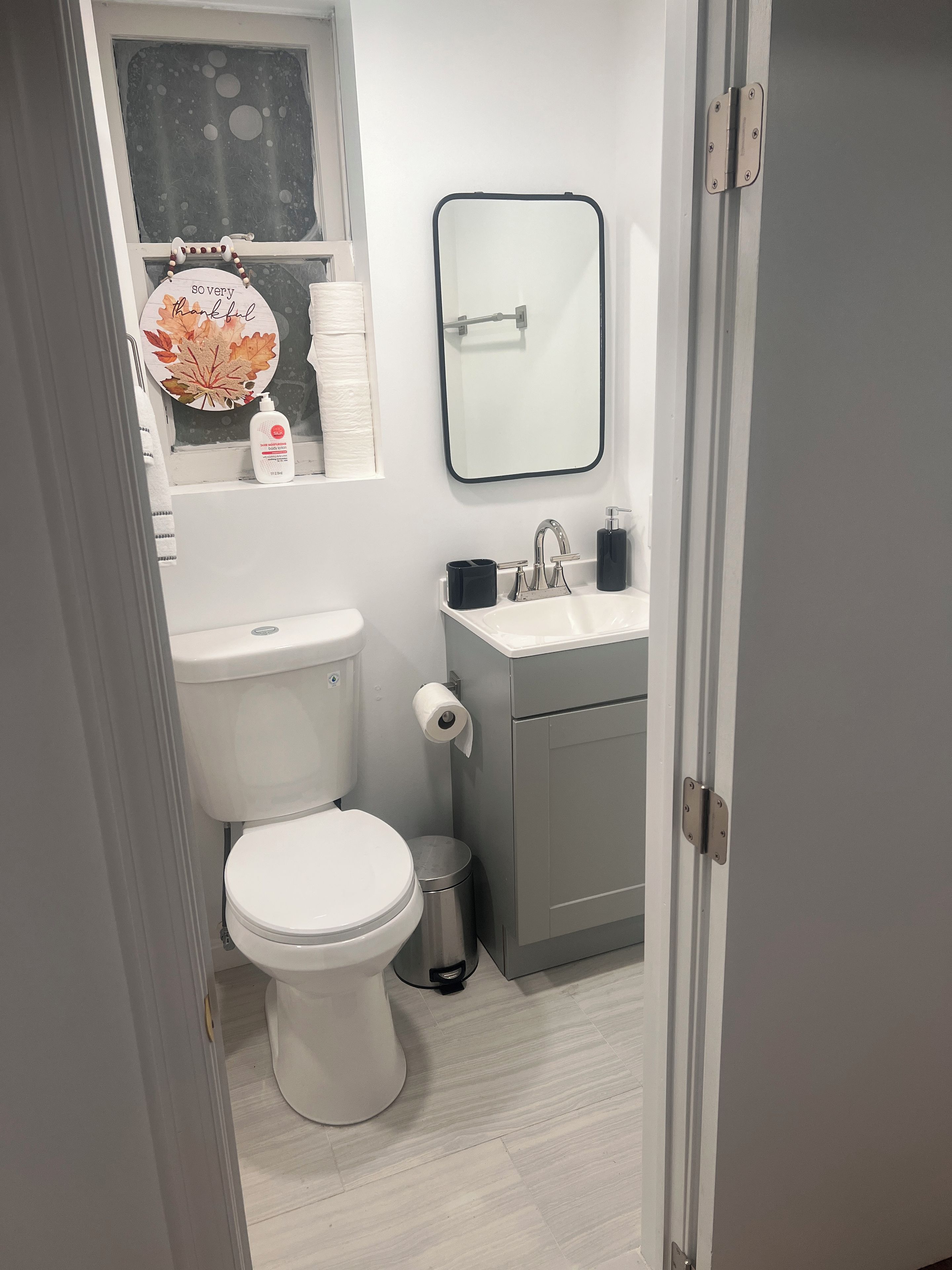 Een kleine badkamer met toilet, wastafel en spiegel.