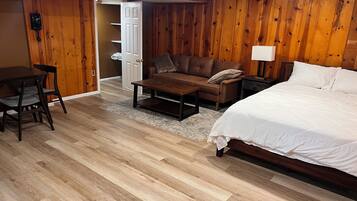 Quarto com cama, sofá, mesa de centro, escrivaninha e paredes de madeira.