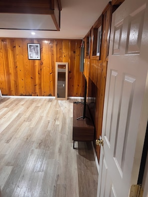 A room with wooden panel walls, a wooden bench, a white door, and a framed picture on the wall. - Brand-New, Newly Renovated Private Suite (Washington)