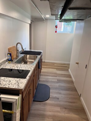 A modern kitchen with a granite countertop, stainless steel sink, and a built-in stove. - Brand-New, Newly Renovated Private Suite (Washington)