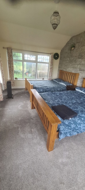 A bedroom with a large bed, a wooden bench, a radiator, and a view of the outdoors through a window.