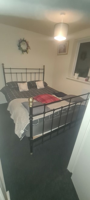 A bedroom with a bed, a window, and a wall-mounted light fixture.