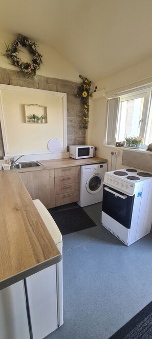 A compact kitchen with a washing machine, microwave, and a built-in oven. - Greystones nawab sleep 25 peak park ..Derbyshire dales..buxton (Buxton)