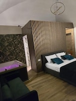Un dormitorio con cama, mesita de noche, sofá, televisor montado en la pared y un separador de madera con listones.