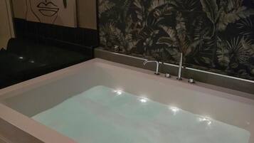 A large, rectangular hot tub with a control panel on the left side.