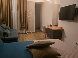 A bedroom with a bed, a desk, a chair, a television, and a wardrobe.