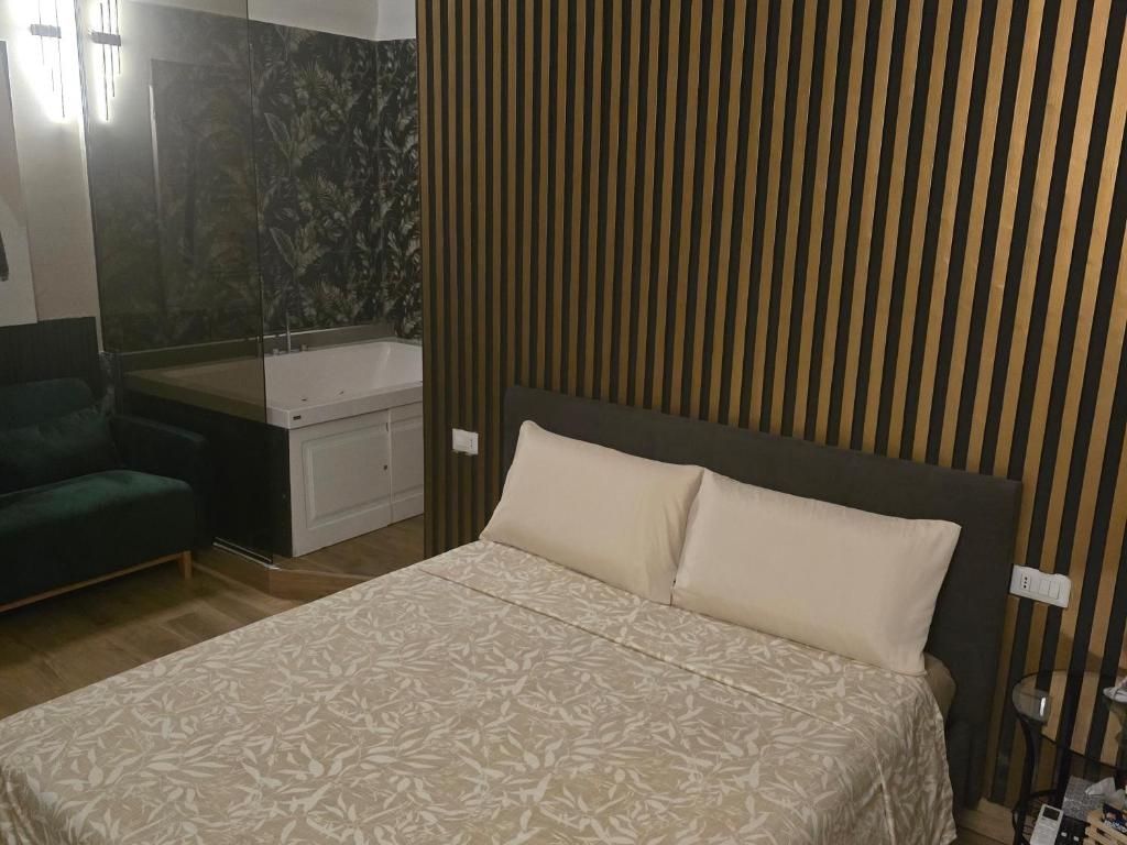 Un dormitorio con cama, sofá verde, bañera y espejo.