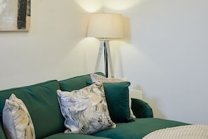A room with a green sofa, a lamp, and a painting on the wall. - Host & Stay | Temperance Mews (Saltburn)
