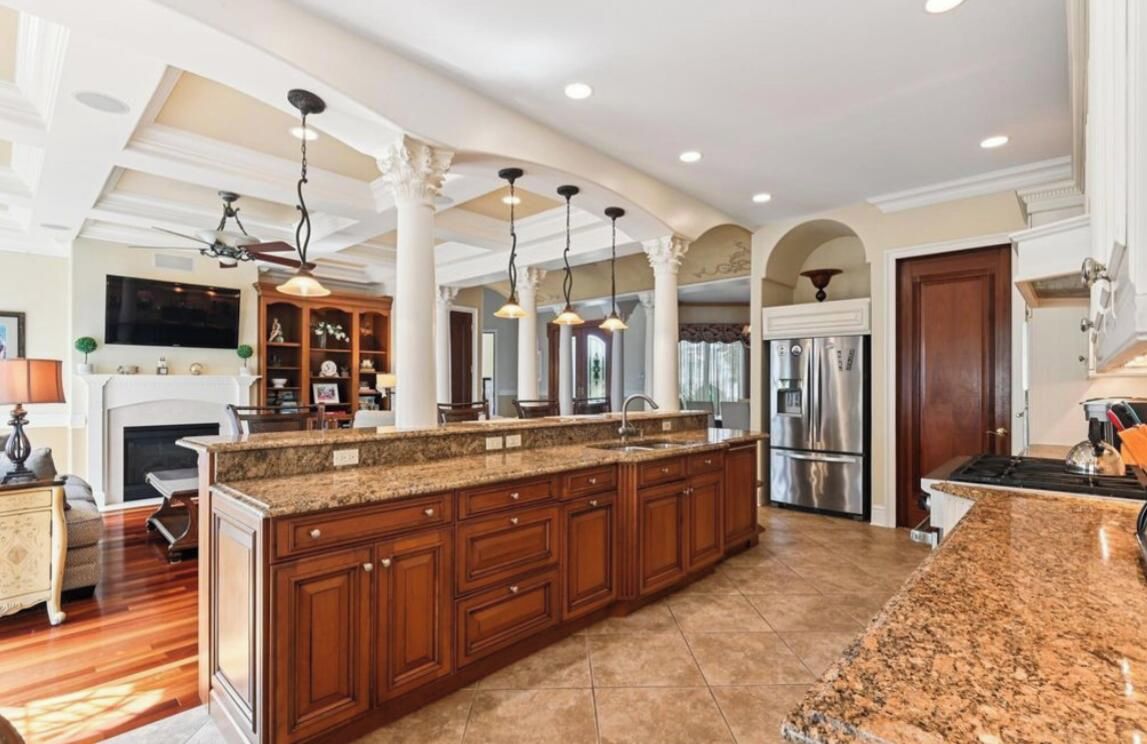 A spacious kitchen with a large island, wooden cabinets, and a modern stove.
