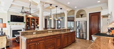 A spacious kitchen with a large island, wooden cabinets, and a modern stove.