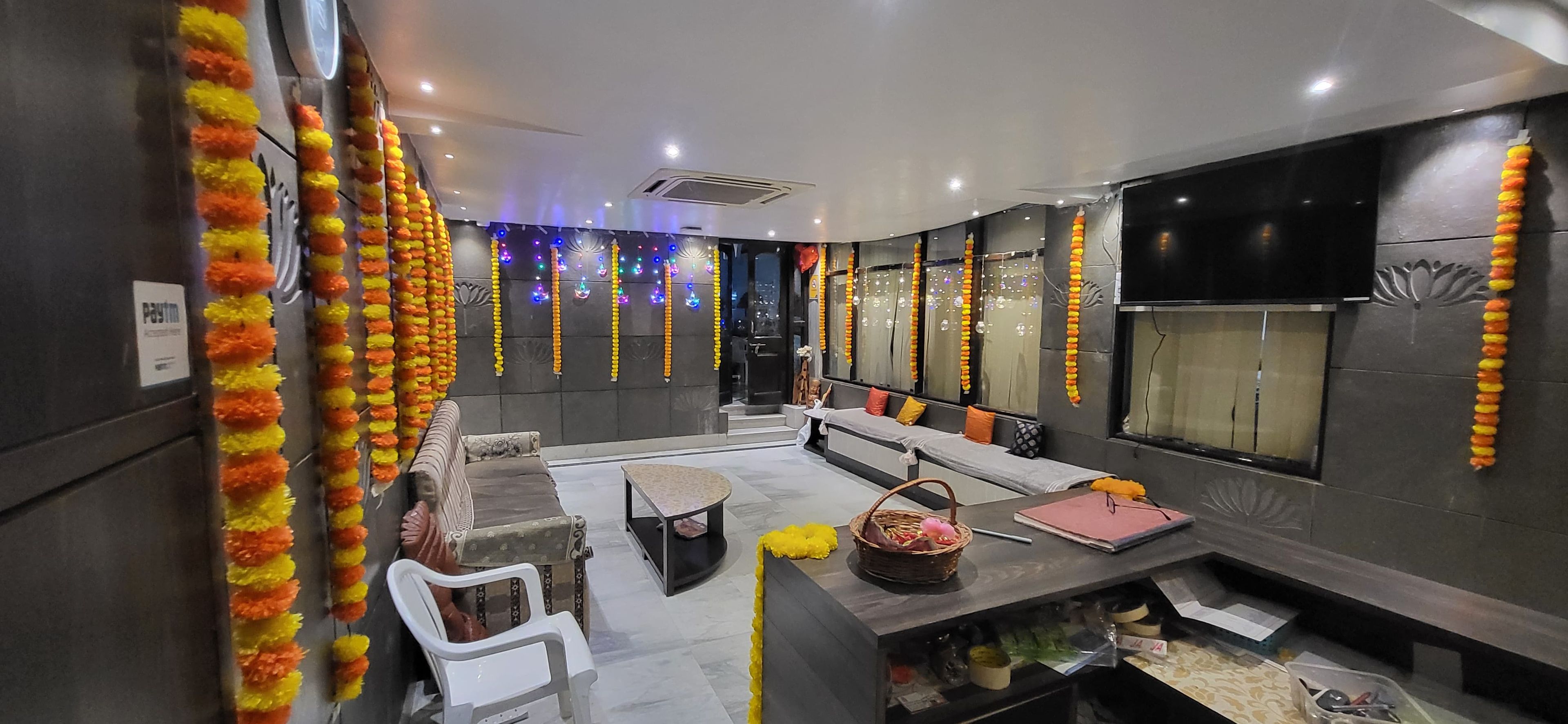 A hotel lobby with a seating area, a reception desk, and a wall decorated with garlands.