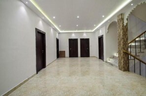 A spacious hallway with a marble floor, multiple doors, and a staircase with a patterned wall. - Hotel Rani Palace (Udaipur)