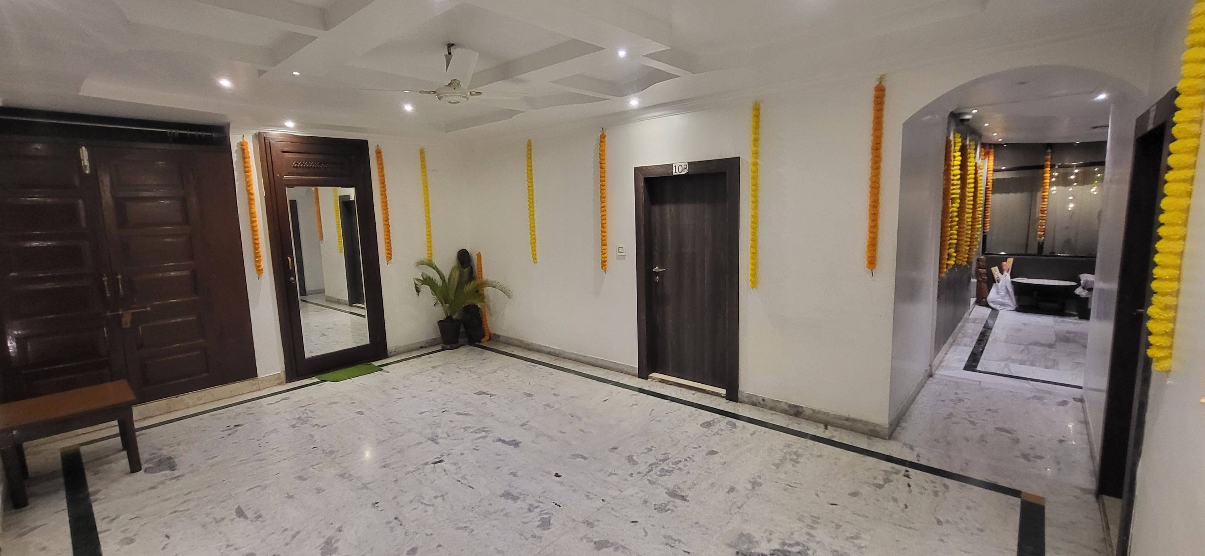 A hotel lobby with marble flooring, a ceiling fan, and a potted plant.