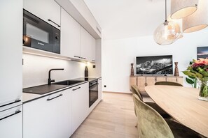 A modern kitchen with white cabinetry, a Bosch microwave, and a black stove. - Laverock – Garden | Parking | Near Lifts | Morzine (Morzine)